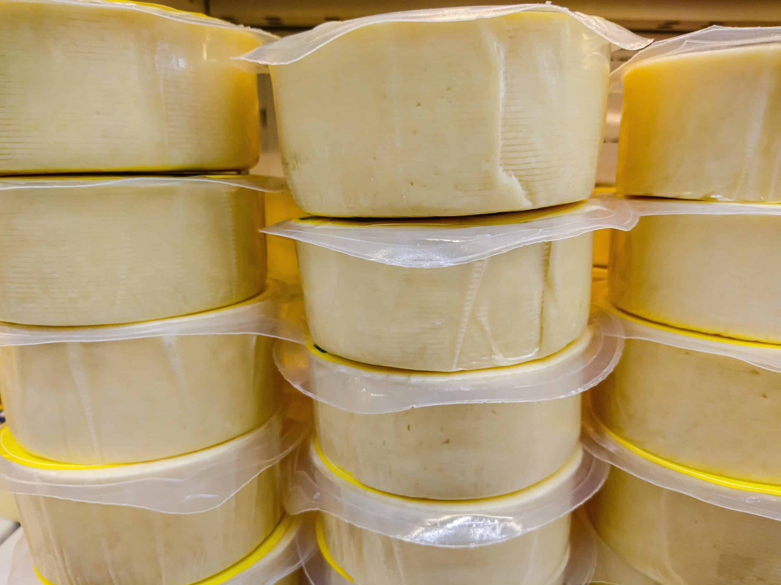 Cheese in a transparent film on the counter of the store, dairy product